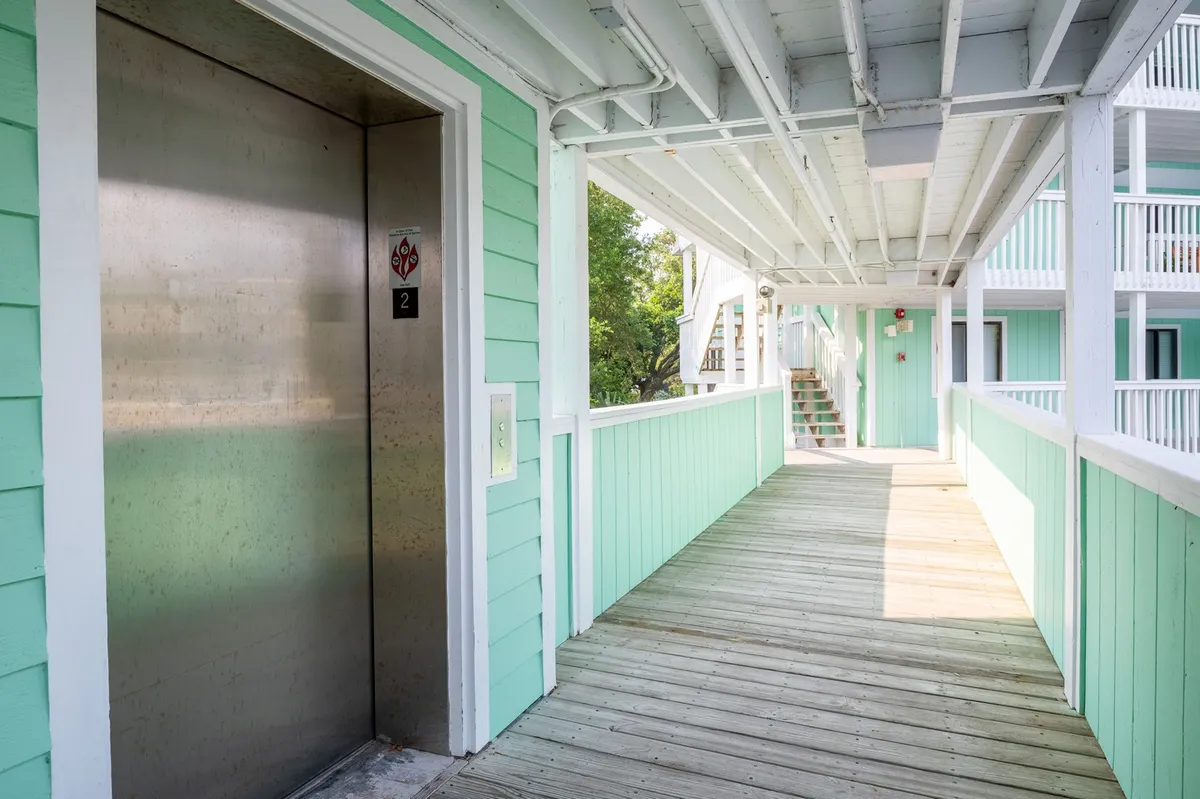 A clear view of the exterior elevator, wooden walkway, and pastel green walls. The wooden boardwalk leads to the elevator, providing a sense of accessibility and the convenience of moving between floors.