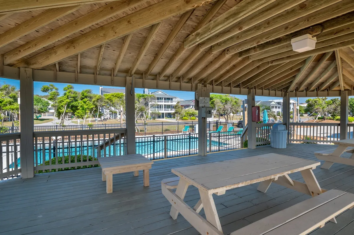 This image captures outdoor picnic tables set near the pool area with surrounding greenery, offering a relaxed environment for social gatherings, grilling, and family meals under the open sky.