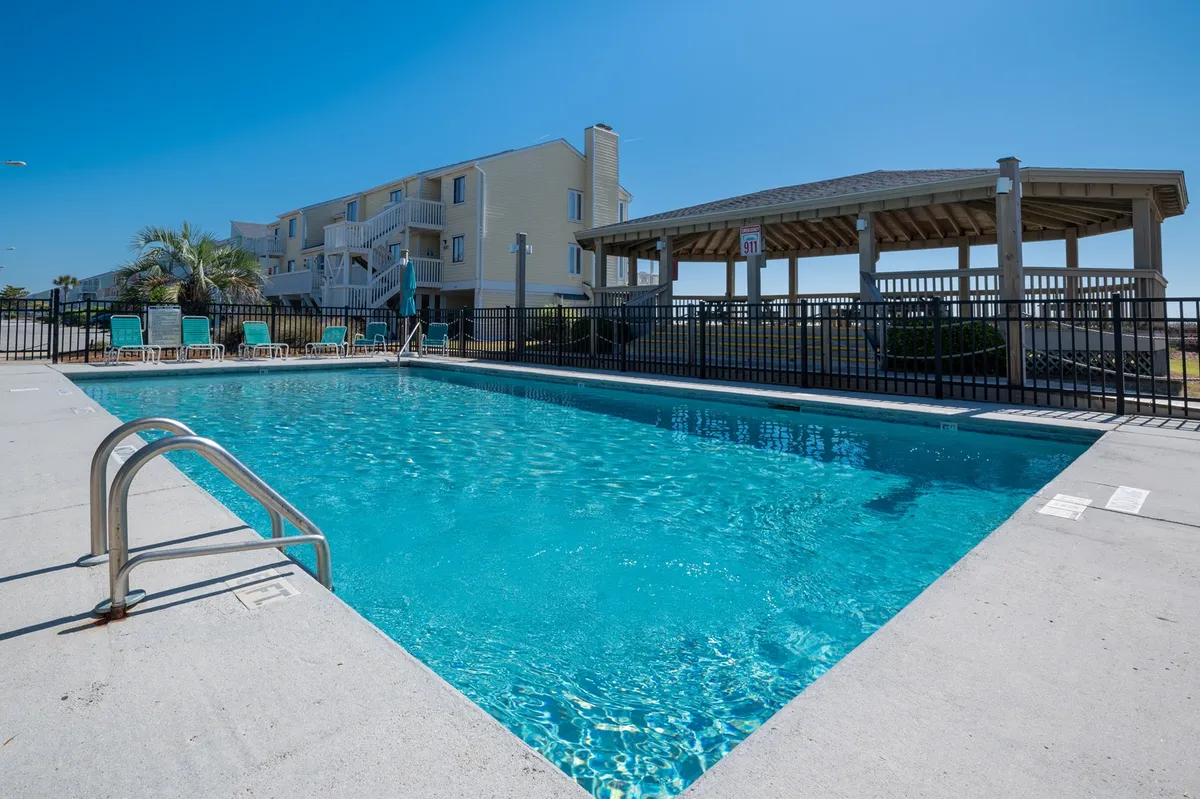 A bright, sunny pool area with lounge chairs and a charming gazebo. Families and friends are seen lounging, swimming, and socializing, creating a lively yet relaxed environment ideal for making memories together.